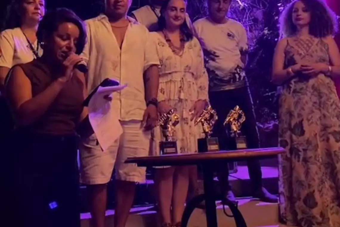 Premiação à noite, com troféus sobre a mesa